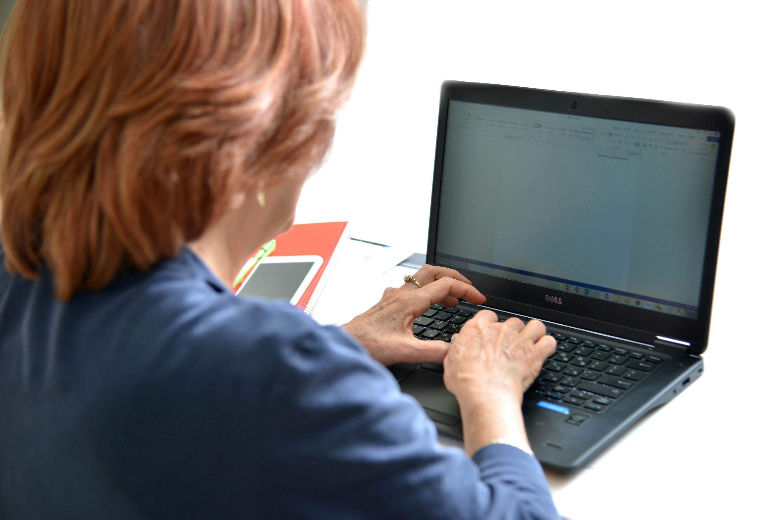 Person working on laptop during online learning session with financial charts visible on screen